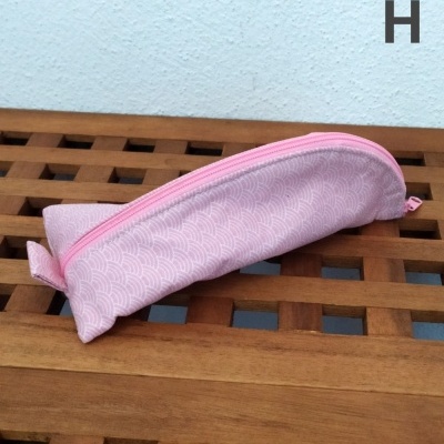 Estojo rosa claro com padrão em ondas sobre mesa de madeira e parede branca