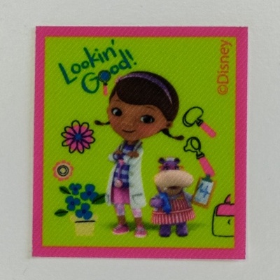 Adesivo quadrado colorido com personagem infantil e hipopótamo de brinquedo, texto 'Lookin' Good!' e fundo verde