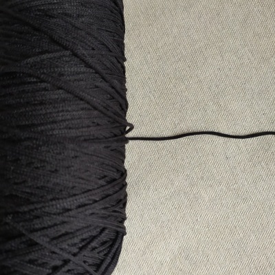 Rolo de fio preto sobre tecido cinzento claro