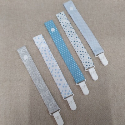 Pegs em tecido azul e cinza com padrões e clips brancos sobre fundo bege