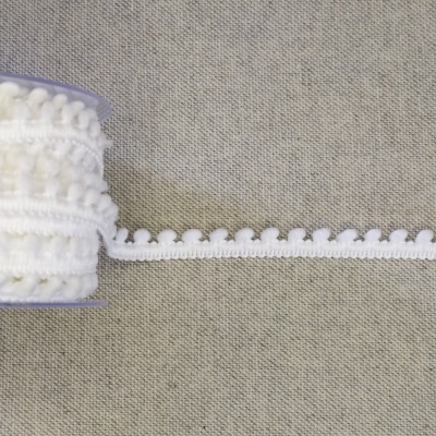 Fita decorativa branca com bolinhas sobre tecido cinza