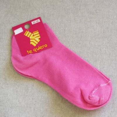 Meia rosa choque com rótulo 'te quiero' em fundo cinzento