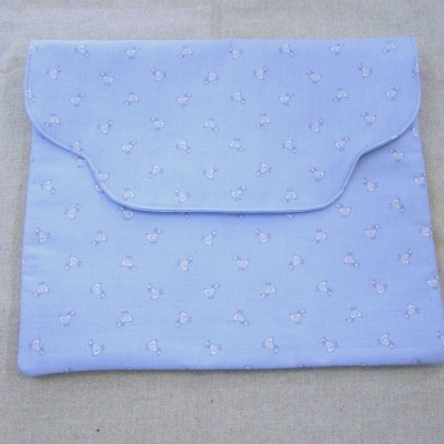 Envelope de tecido azul claro com pequenos desenhos brancos e rosas e botão de pressão