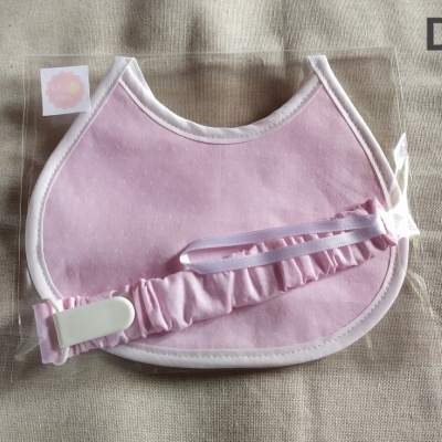 Babete cor-de-rosa com fita elástica e presilha em embalagem plástica