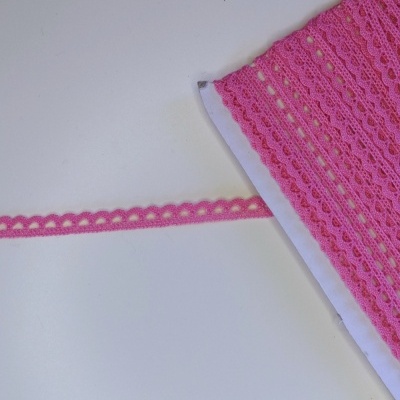 Rolo de renda rosa com padrão decorativo sobre fundo branco