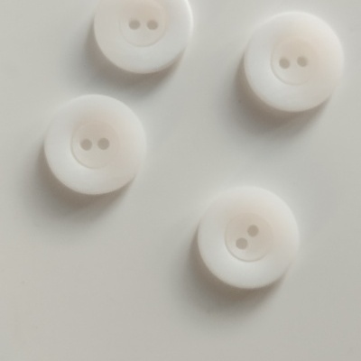 Quatro botões brancos redondos com dois furos sobre superfície branca