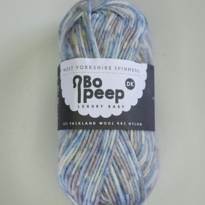 Novelo de lã azul claro, creme e cinza com etiqueta preta e branca