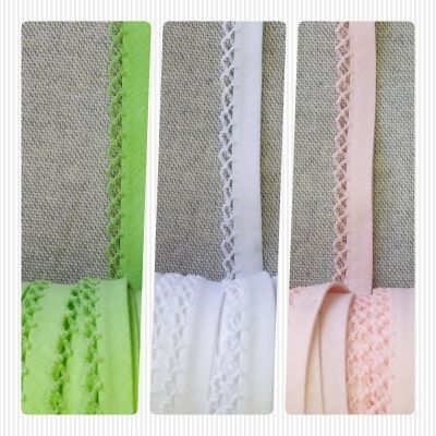 Três fitas rendadas coloridas verde, branco e rosa sobre fundo cinza