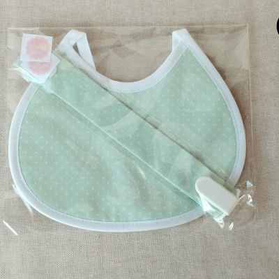 Babete de bebé verde claro com bolinhas e fita com clip em plástico transparente