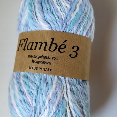 Novelo de lã azul, branco e lilás com etiqueta castanha e texto Cor 58 ao fundo