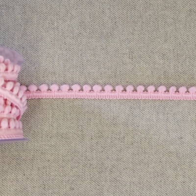 Fita decorativa rosa claro com pompons pequenos enrolada num carretel