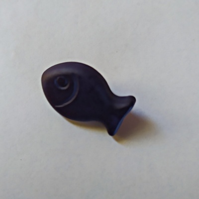 Figura decorativa azul escuro em forma de peixe sobre superfície branca