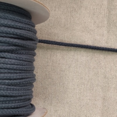 Rolo de cordão azul escuro em carretel sobre tecido bege com a palavra 'Azul'