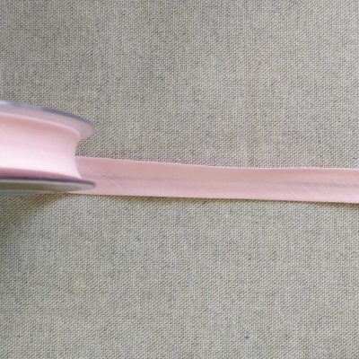 Rolo de fita rosa clara em tecido sobre fundo cinzento com texto Cor 18