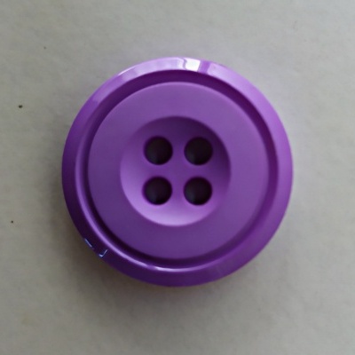 Botão roxo de plástico com quatro furos sobre fundo bege