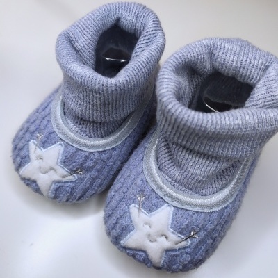 Sapatilhas de bebé cinzentas com estrela branca bordada na frente.