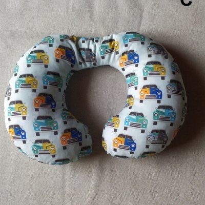 Almofada de pescoço branca com padrão de carros coloridos sobre fundo bege