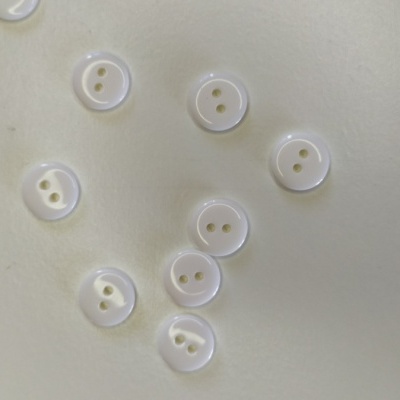 Oito botões brancos pequenos com duas casas sobre superfície clara