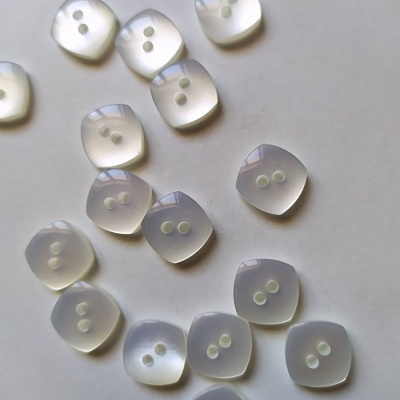 Botões quadrados translúcidos com dois furos em superfície branca