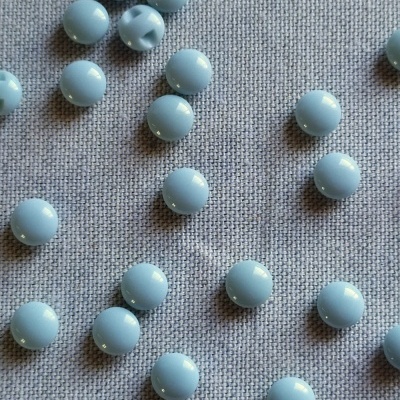 Contas redondas azuis claras sobre tecido cinzento com a palavra 'Azul' em preto