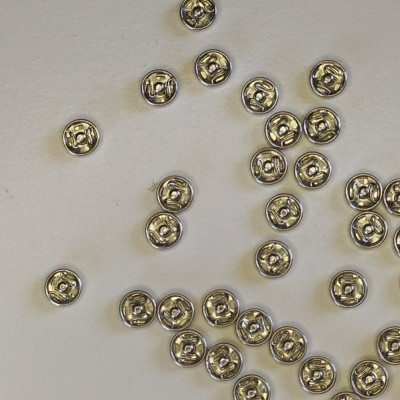 Pequenas molas metálicas prateadas sobre superfície clara