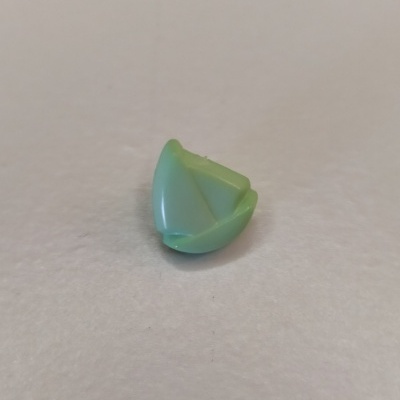 Peça pequena de plástico verde claro de forma triangular sobre superfície branca