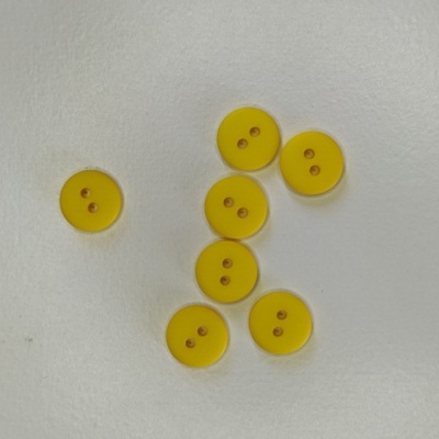Sete botões amarelos redondos com dois orifícios sobre fundo branco