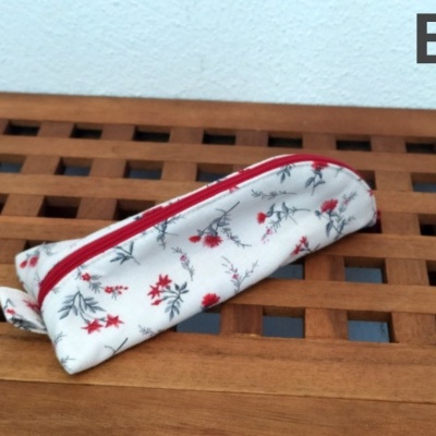 Estojo floral branco com fecho vermelho sobre tábua de madeira