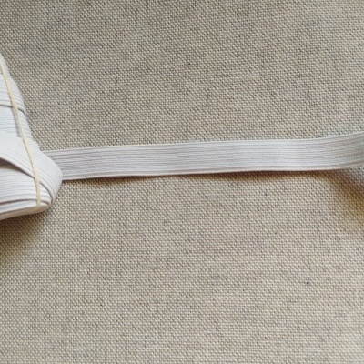 Fita elástica branca de 12 mm sobre tecido bege