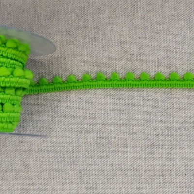 Fita decorativa verde com bolinhas em rolo sobre tecido cinzento