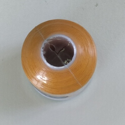 Rolo de linha de costura cor laranja visto de cima