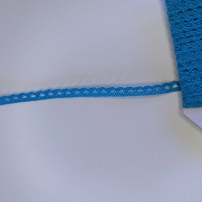 Rolo de renda azul com padrão decorativo branco sobre superfície branca