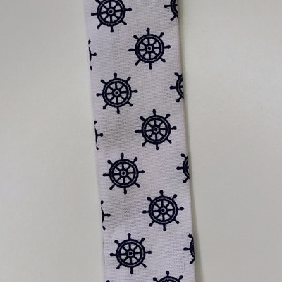 Tira de tecido com padrão náutico e clipe branco sobre superfície clara