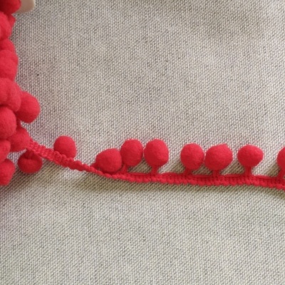 Fita vermelha com pompons em tecido bege
