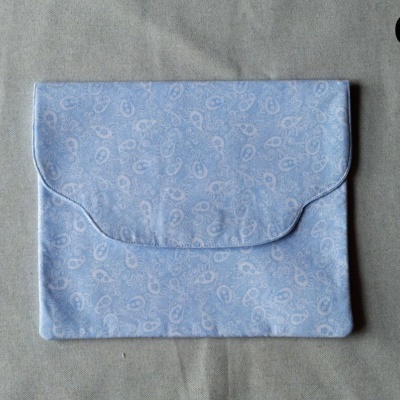 Carteira pequena azul claro com padrão paisley branco sobre superfície cinzenta