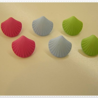 Seis objetos em forma de concha coloridos sobre mesa bege