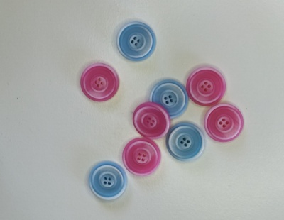 Botões de plástico azuis e cor-de-rosa sobre fundo branco