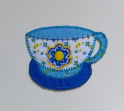 Aplicação decorativa tecido chávena azul com flor e folhas verdes