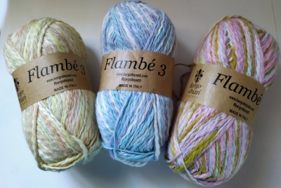 Três novelos de lã coloridos da marca Flambé 3 com rótulos marrons