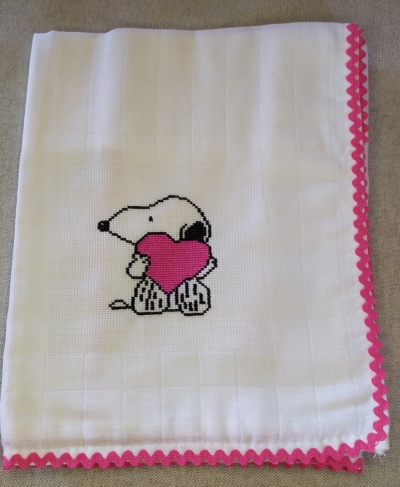 Pano branco com bordado do Snoopy segurando um coração rosa e borda decorada rosa