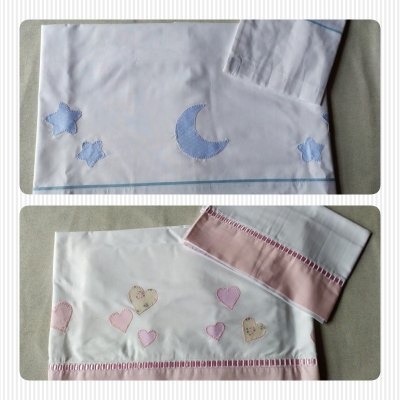 Lençóis infantis bordados com motivos de lua, estrelas e corações em azul e rosa