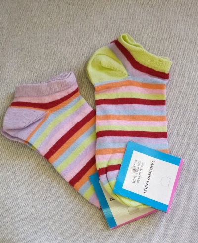 Meias curtas coloridas com riscas e etiqueta de tamanho único sobre fundo cinzento.