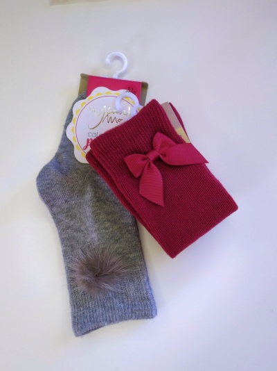 Meias infantil cinzenta com pompom e rosa com laço em malha, com etiqueta pendurada.