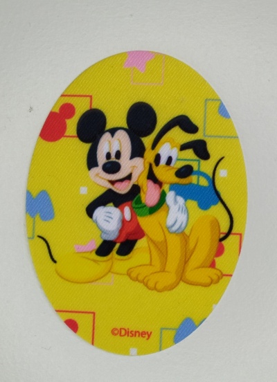 Adesivo oval amarelo com Mickey Mouse e Pluto de desenho animado e texto ©Disney.