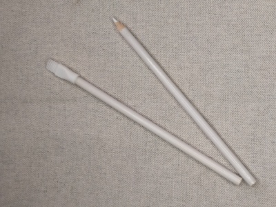 Dois lápis de cor branco sobre tecido bege