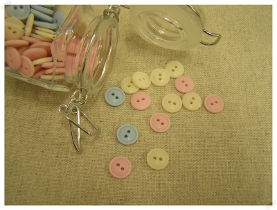 Botões de plástico pastel em frascos de vidro e sobre tecido bege