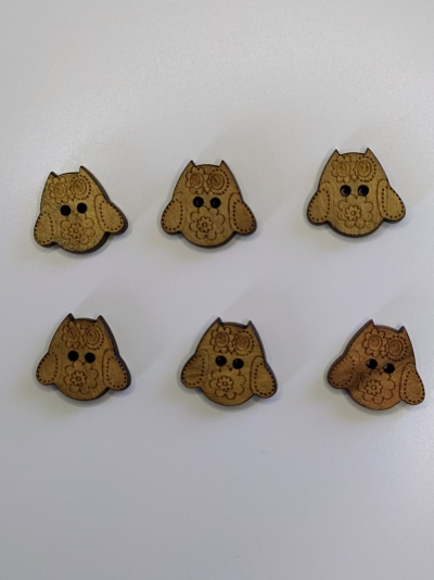 Seis botões de madeira em forma de cão com detalhes gravados sobre superfície branca