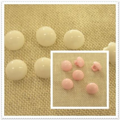 Botões redondos em resina branca e rosa sobre tecido bege