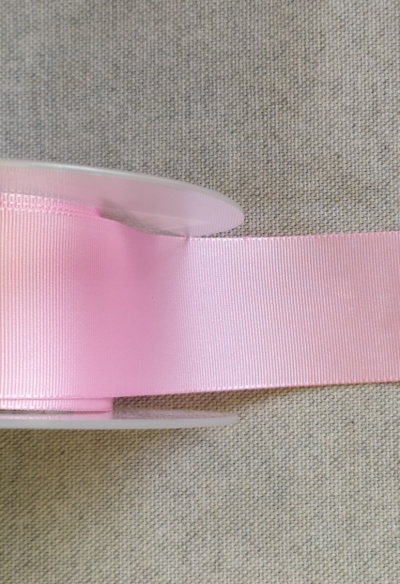 Rolo de fita cor-de-rosa claro em superfície de tecido cinzento