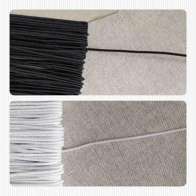 Cordões elásticos preto e branco sobre tecido bege com textura